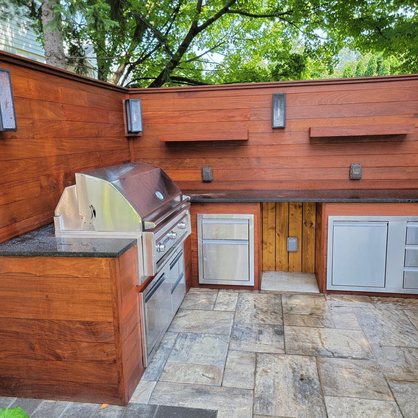 An outdoor kitchen with stainless steel appliances and wooden cabinets