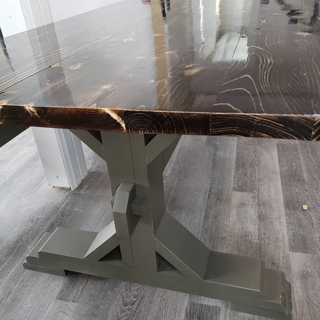 A wooden table with a gray base is sitting on a wooden floor.