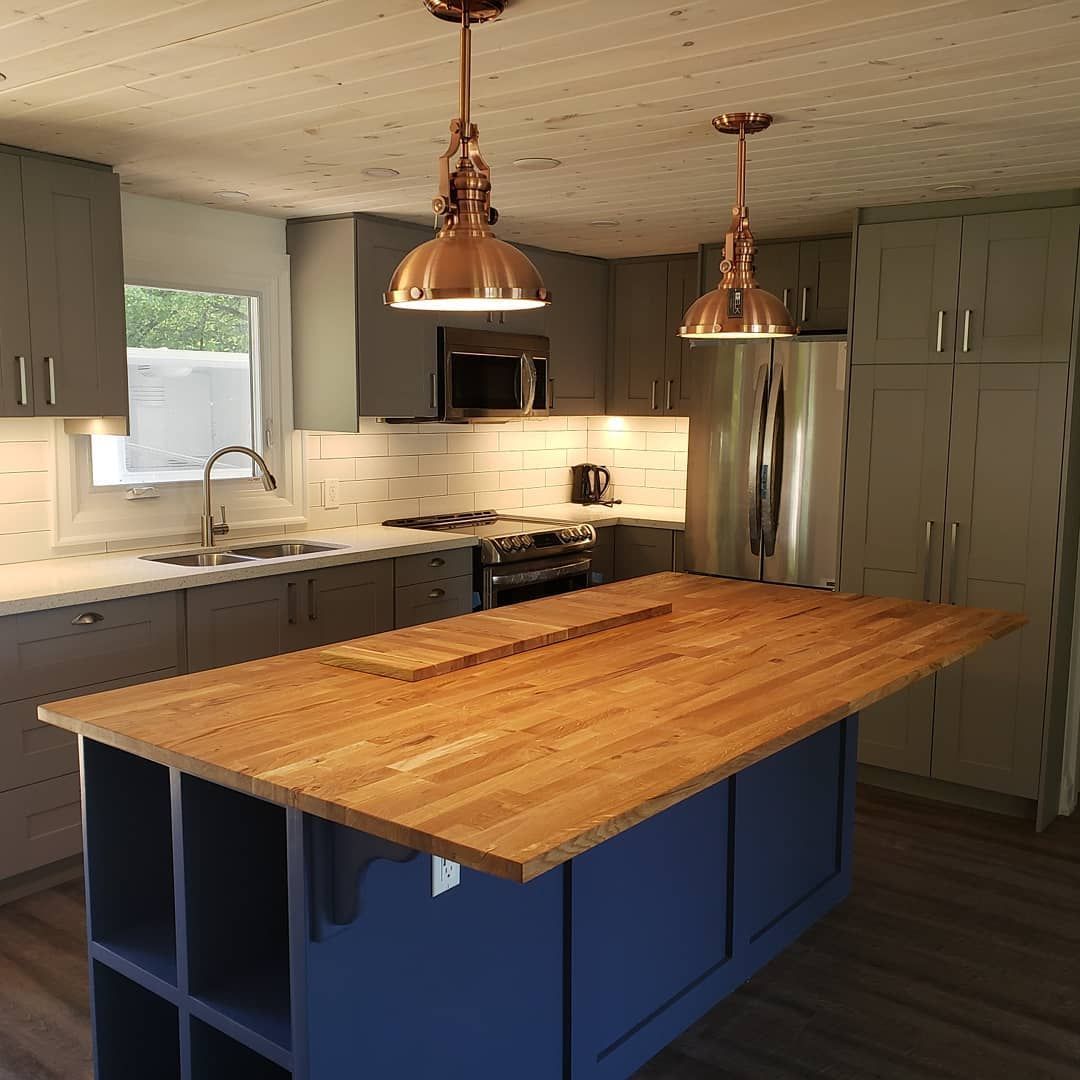 A kitchen with a large wooden island in the middle
