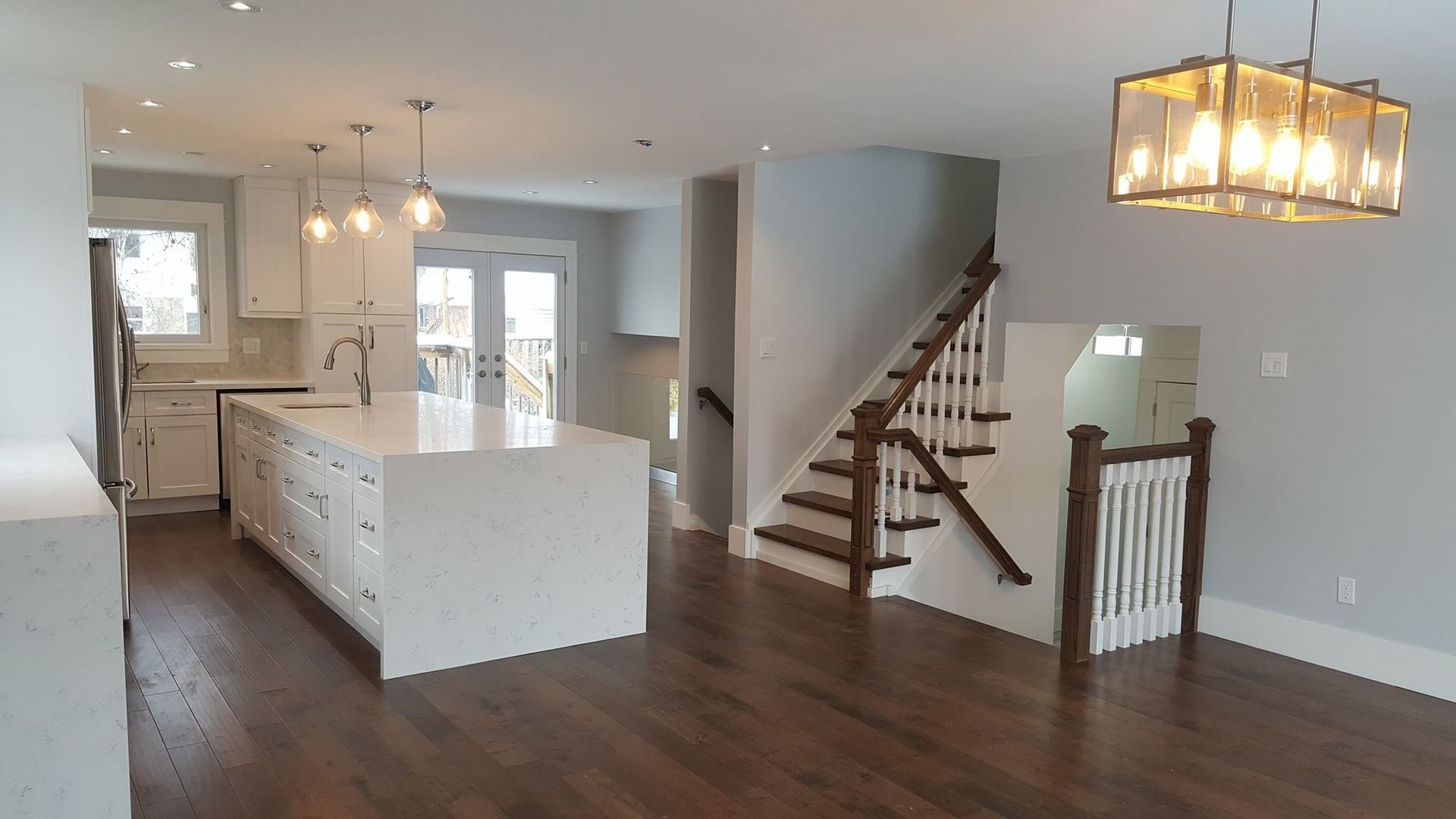 A kitchen with white cabinets and a wooden staircase