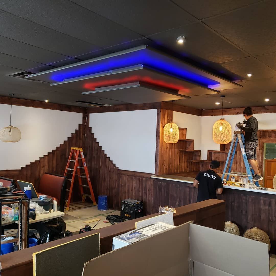 A man standing on a ladder in a room with a sign that says ' a ' on it