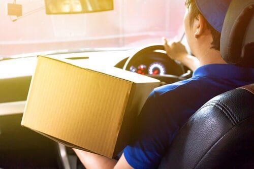 Delivery man driving a truck with cardboard package — Delivery Services in El Paso, TX