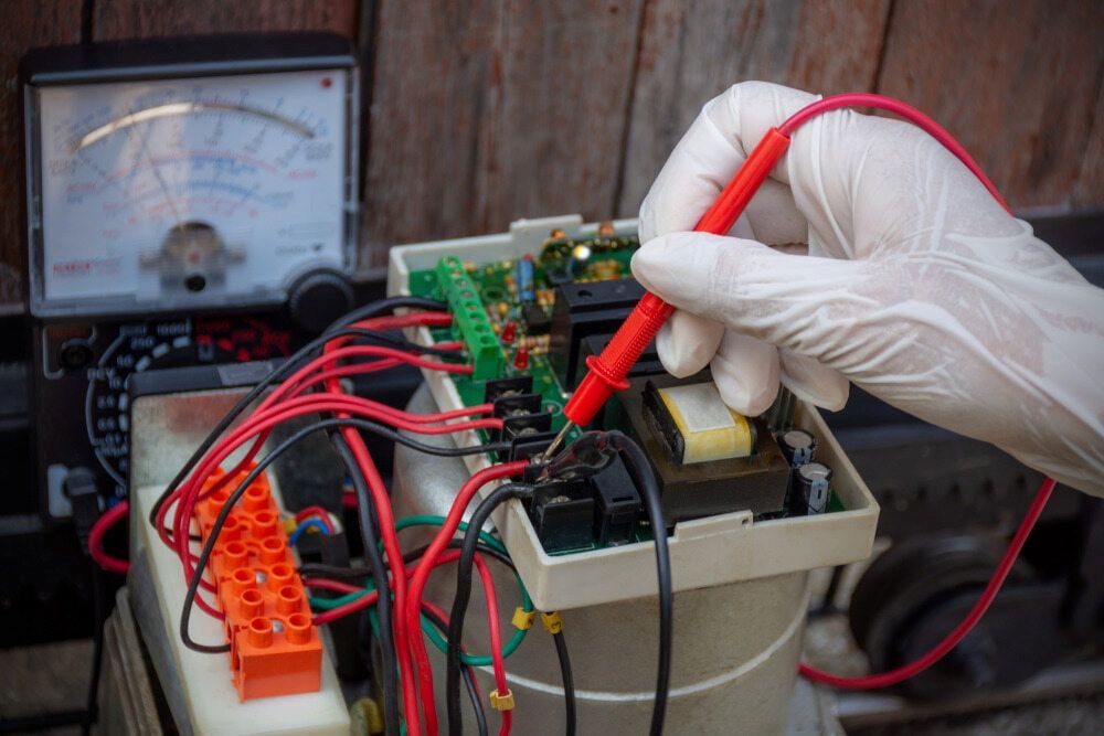 A Person Is Using A Multimeter To Test A Circuit Board — Lex Electrix In West End, QLD