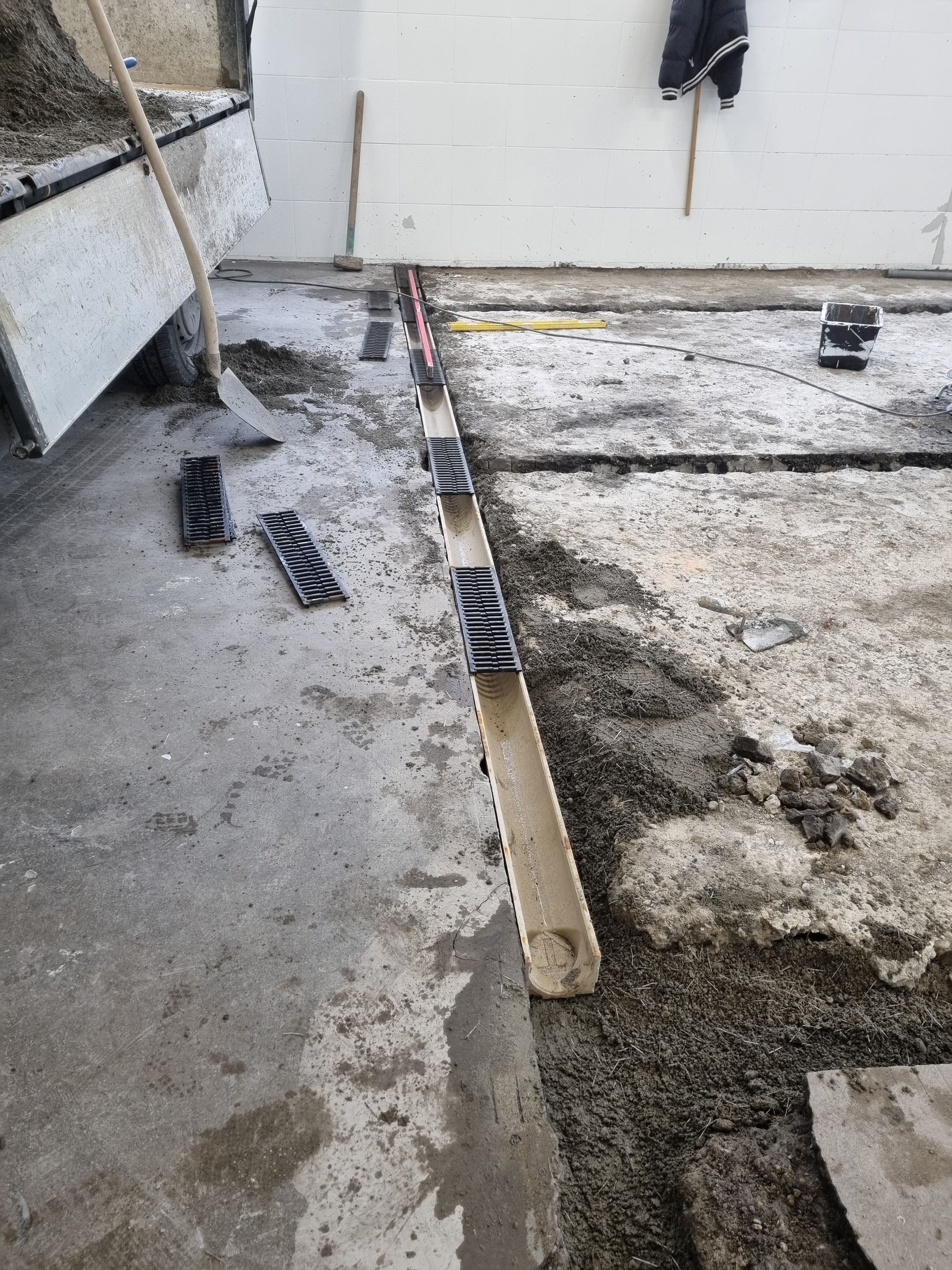 Un caniveau avec des composants en plastique noir, installé dans une dalle de béton, en cours de construction.