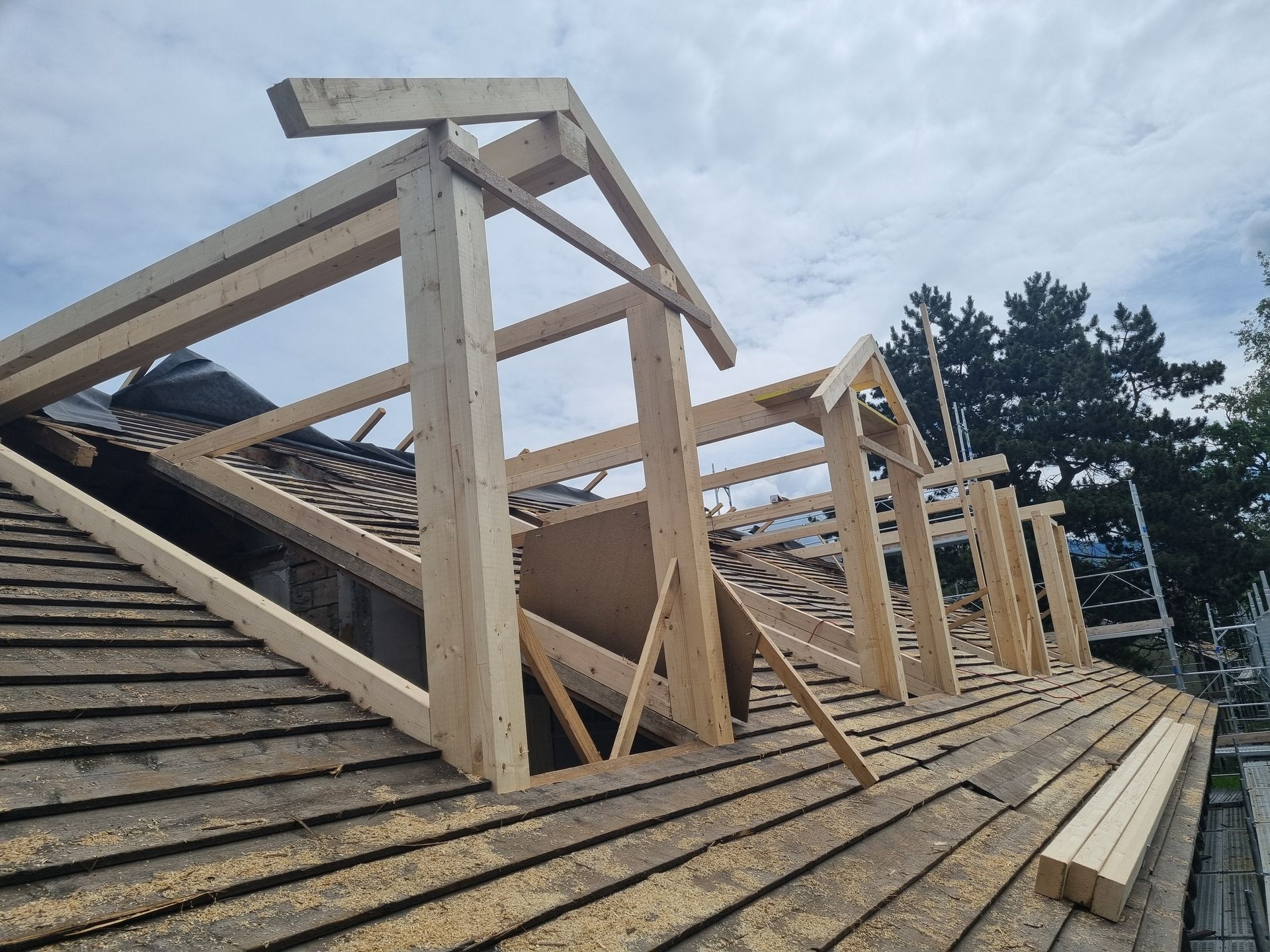 Cadres en bois de trois lucarnes installées sur un toit en pente en construction.