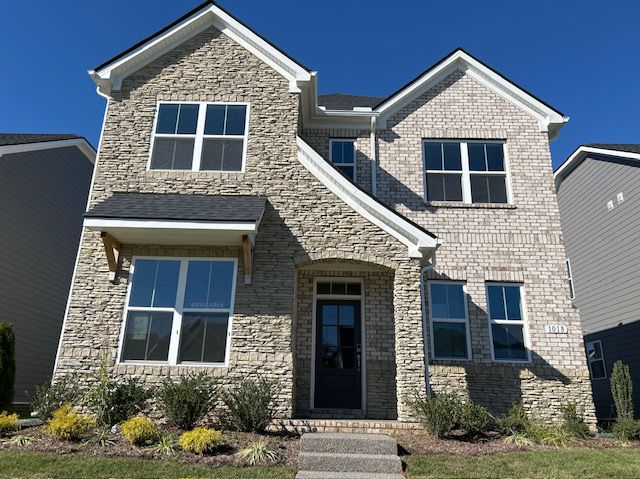 Two-story brick house with dark door and windows; blue sky.