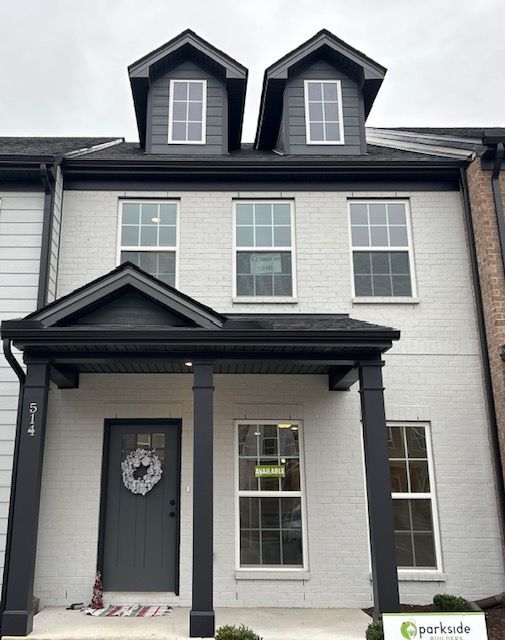 White brick townhome with black trim, two dormers, and a gray front door.