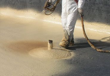 A man is spraying foam on a concrete surface.