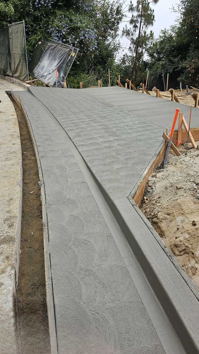 A concrete driveway is being built on a dirt road.