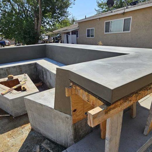 A concrete deck is being built in front of a house.