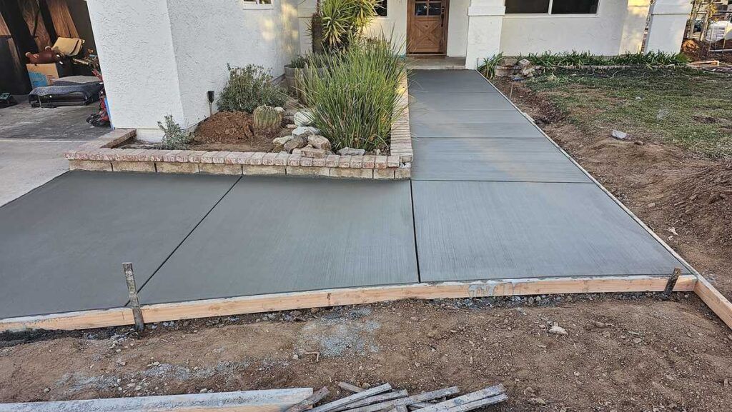 A concrete walkway is being built in front of a house.