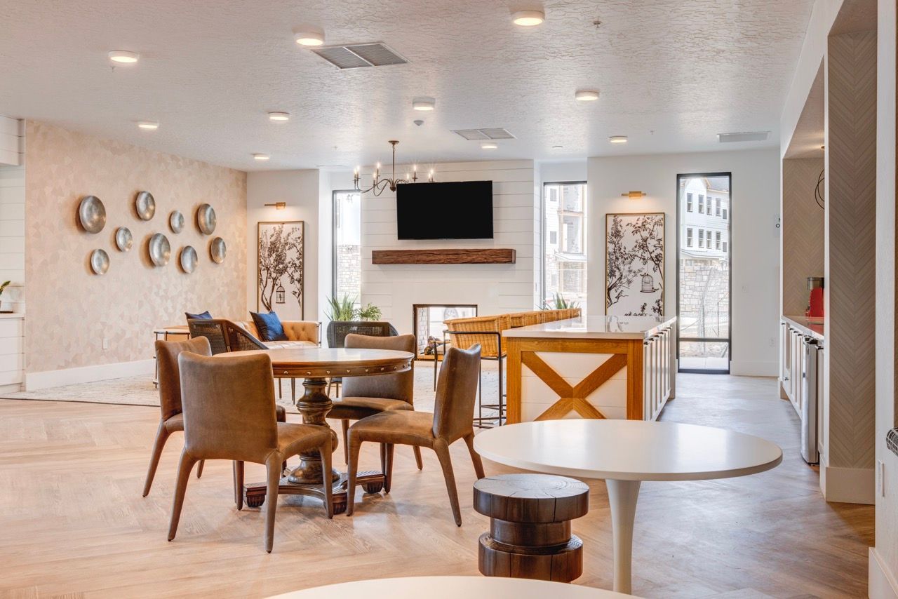 Aria modern communal lounge with round table, chairs, fireplace, TV, and kitchenette.