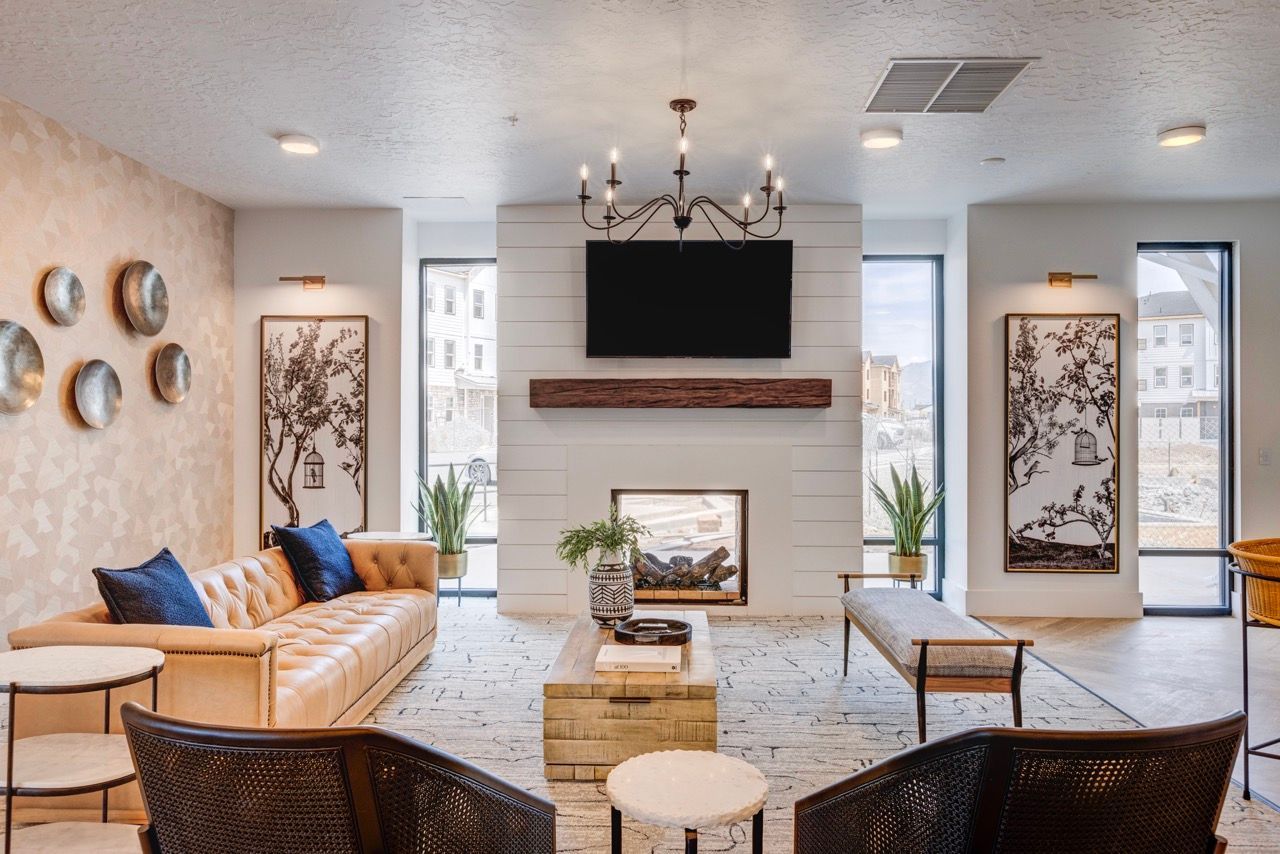 Aria  lounge with a beige tufted sofa, armchairs, fireplace, and a mounted TV.