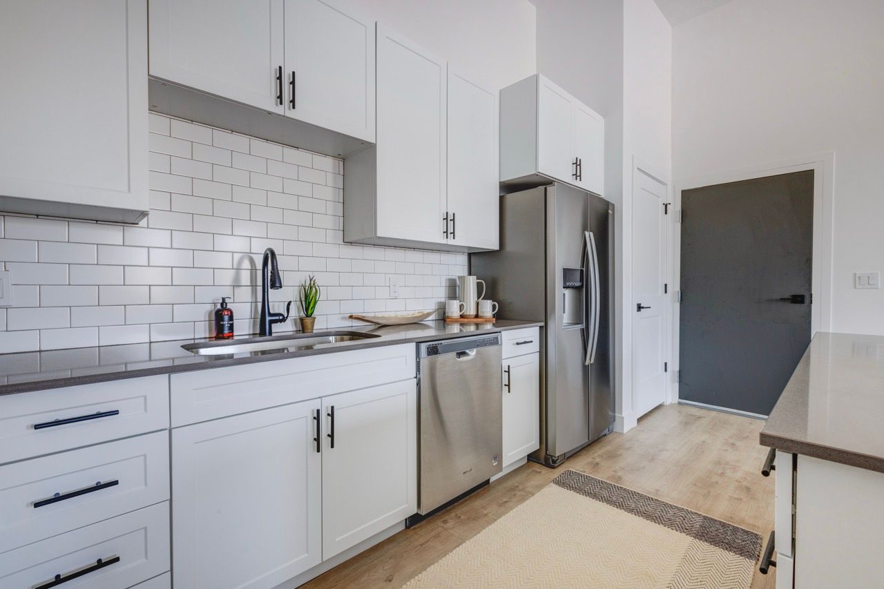 Modern kitchen with white cabinets, a subway tile backsplash, and stainless steel appliances.