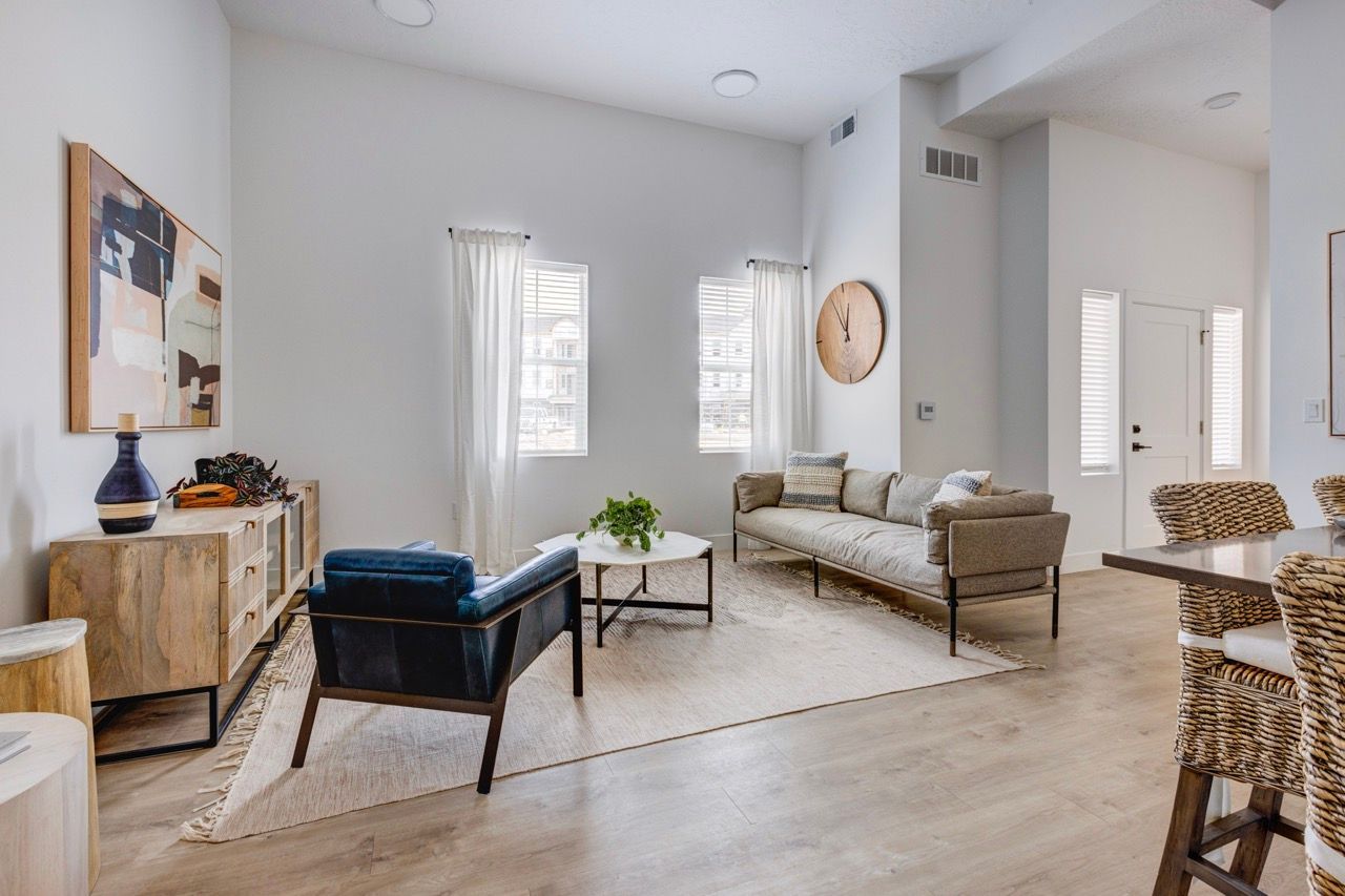 Aria apartment living room with beige sofa, blue armchair, coffee table, and woven dining chairs.