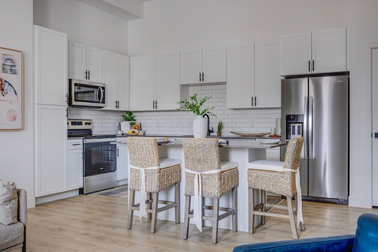 Aria kitchen with an island, wicker bar stools, and stainless steel appliances.