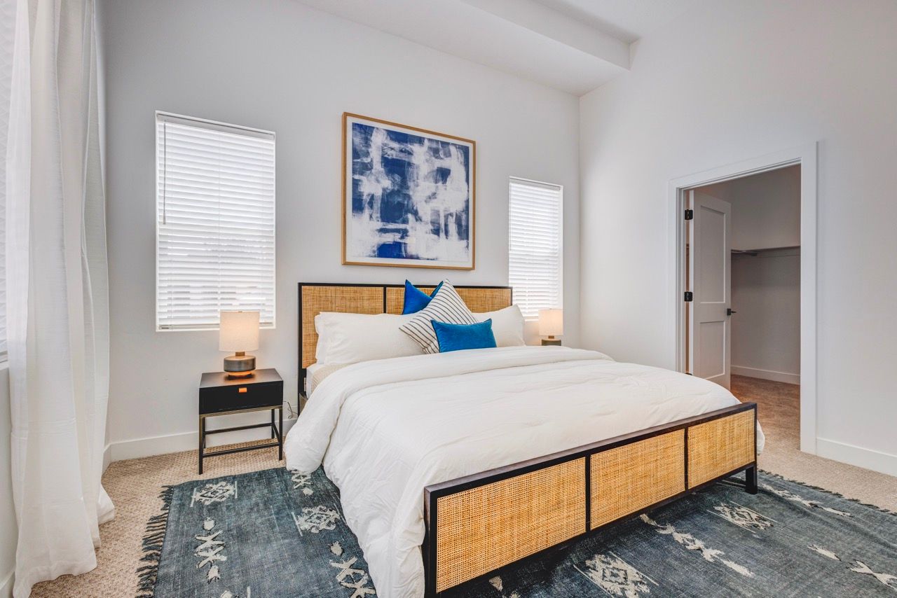 Aria Bedroom featuring a king bed with woven headboard, two nightstands, and blue accent pillows.