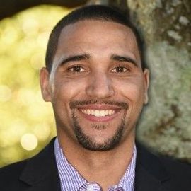 a man with a beard and a suit is smiling for the camera .