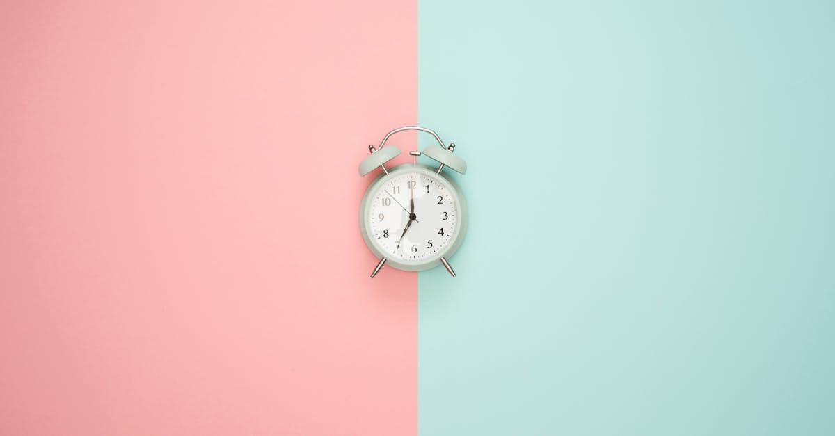 an alarm clock is sitting on a pink and blue background .