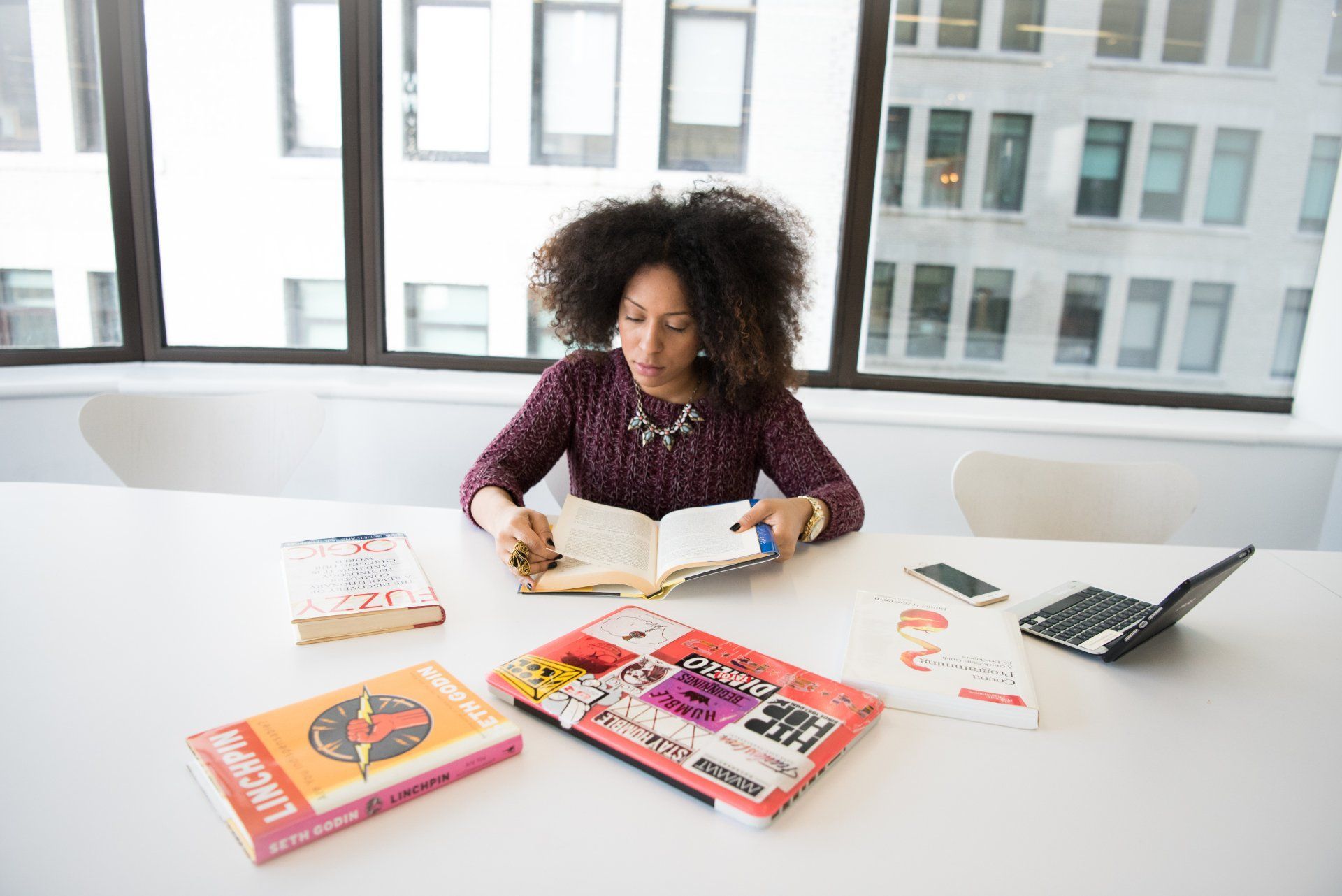 a woman is sitting at a table reading a book .