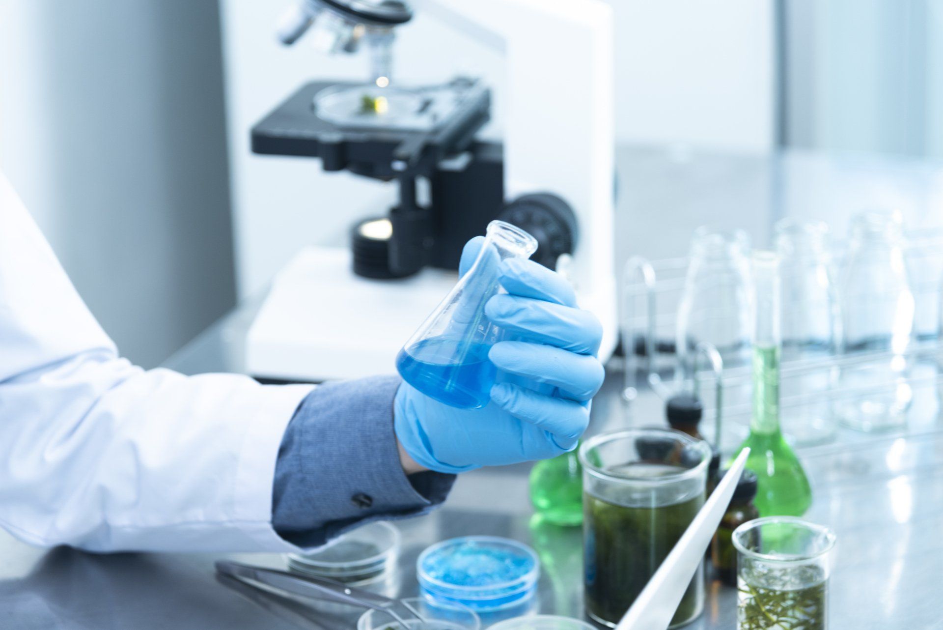 A scientist is pouring a blue liquid into a beaker in a laboratory.