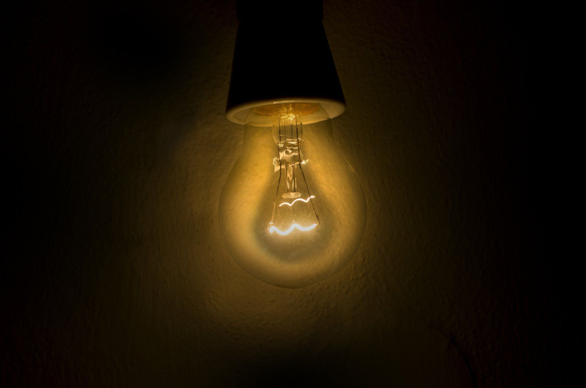 A light bulb is hanging from a ceiling in the dark.