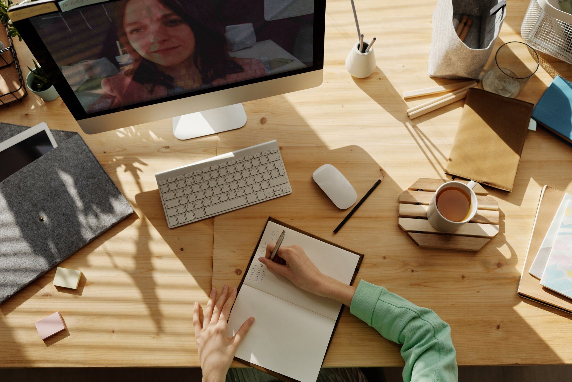 A person is sitting at a desk with a computer and a notebook.