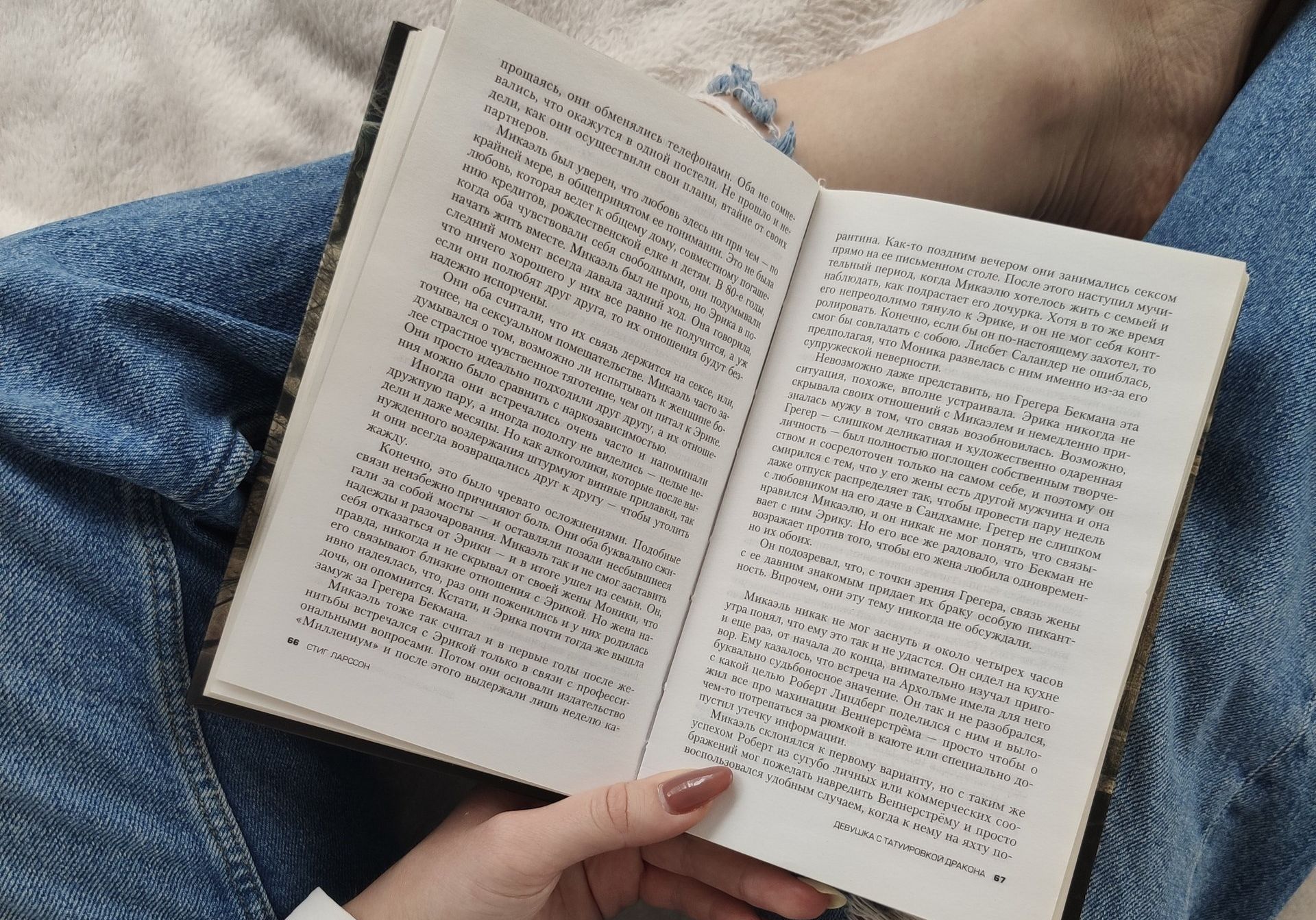 A person is reading a book while laying on a bed.