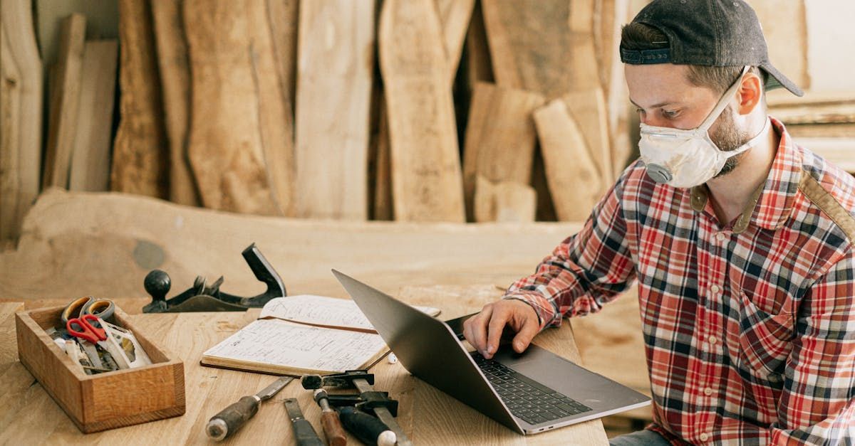 A man wearing a mask is using a laptop computer.