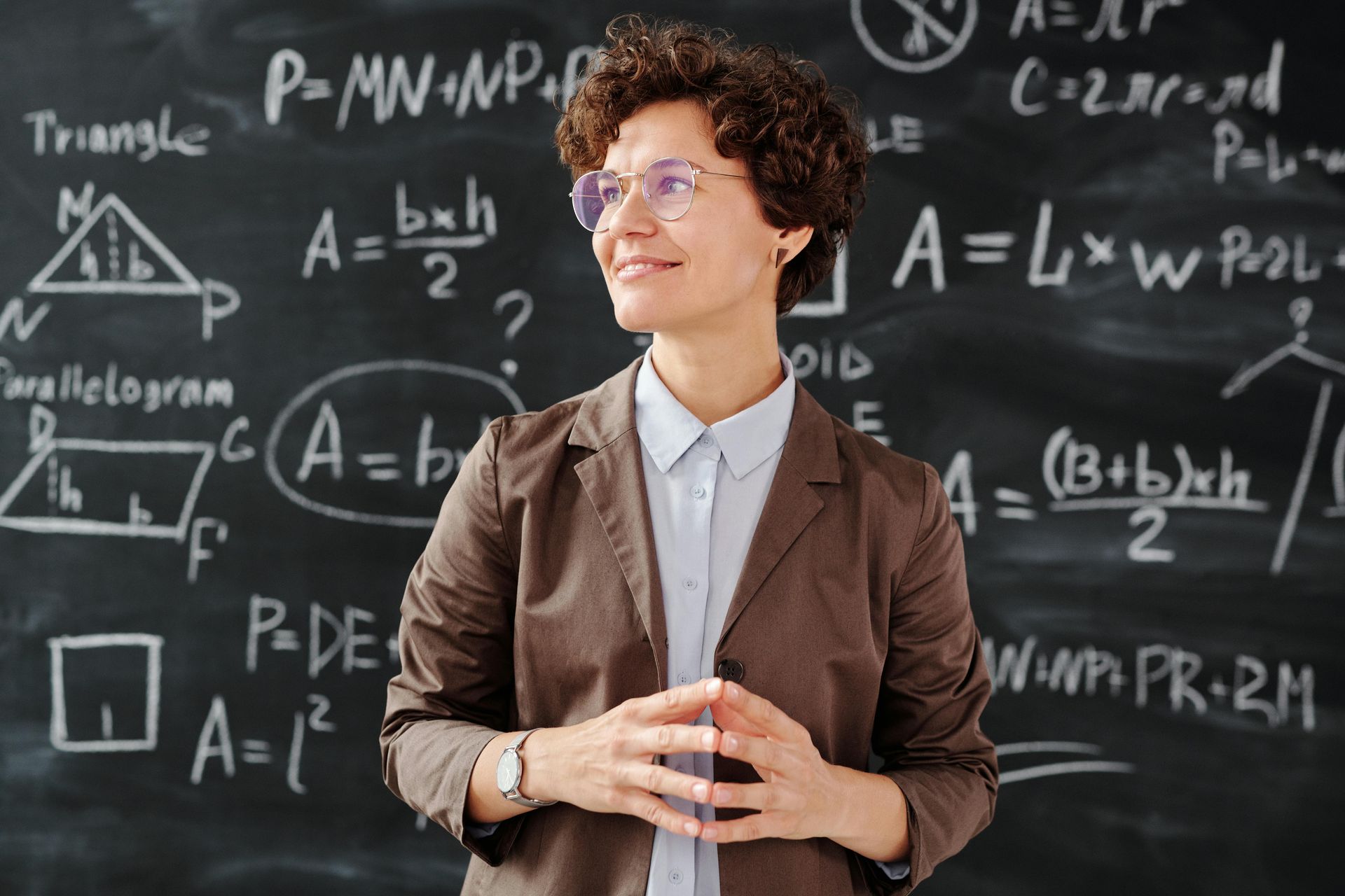 A woman is standing in front of a blackboard with math equations on it.