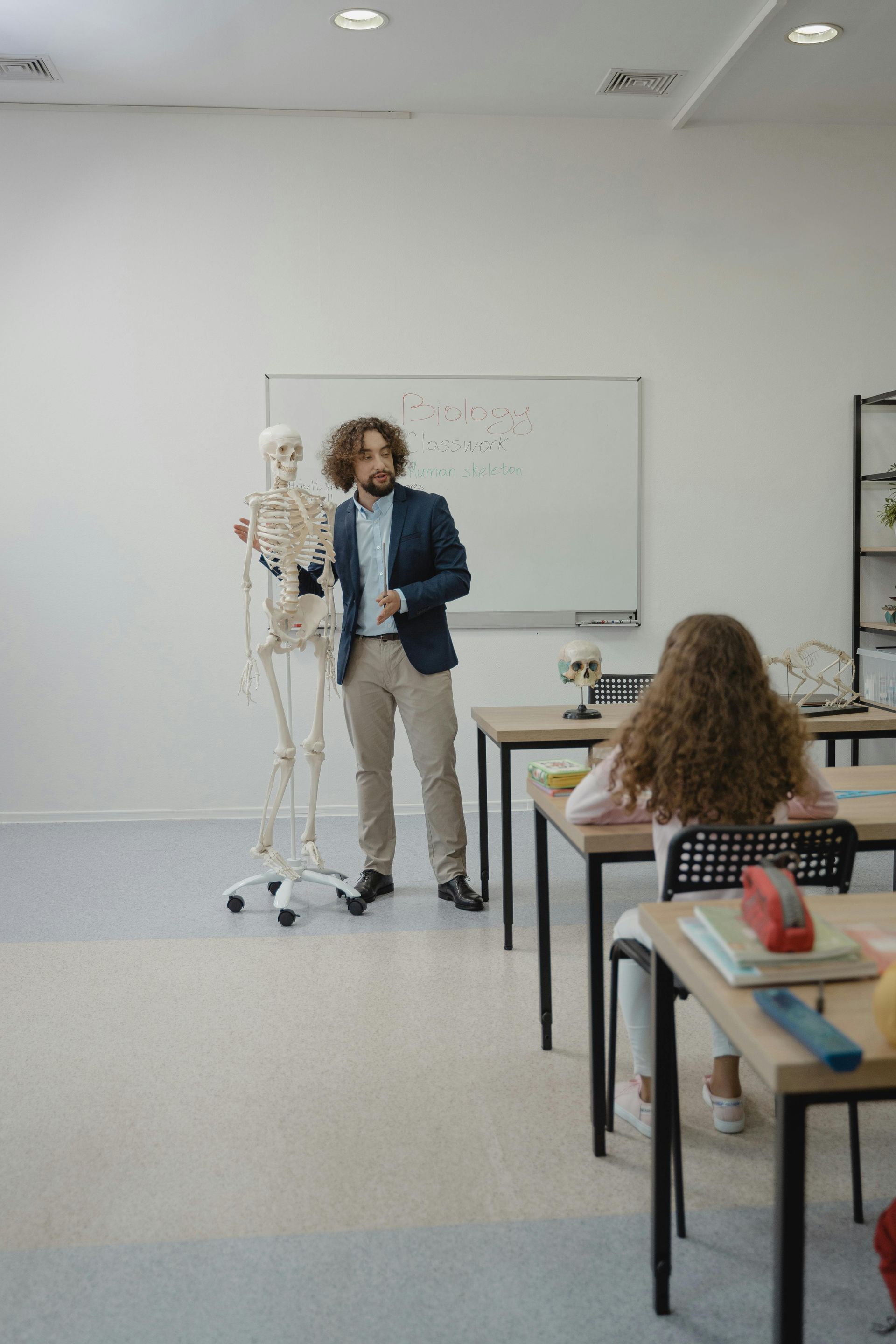A man is standing next to a skeleton in a classroom.