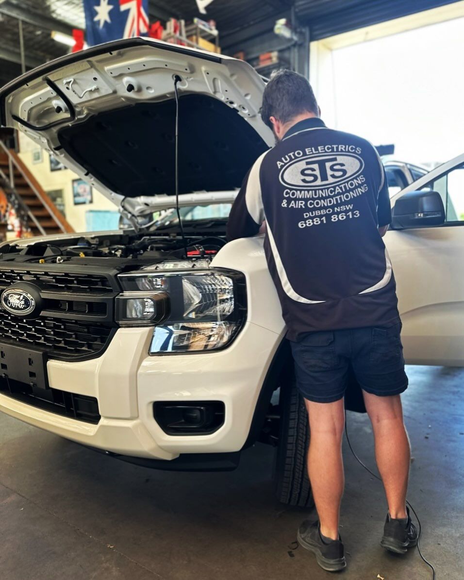 A man is working on the engine of a white truck in a garage.