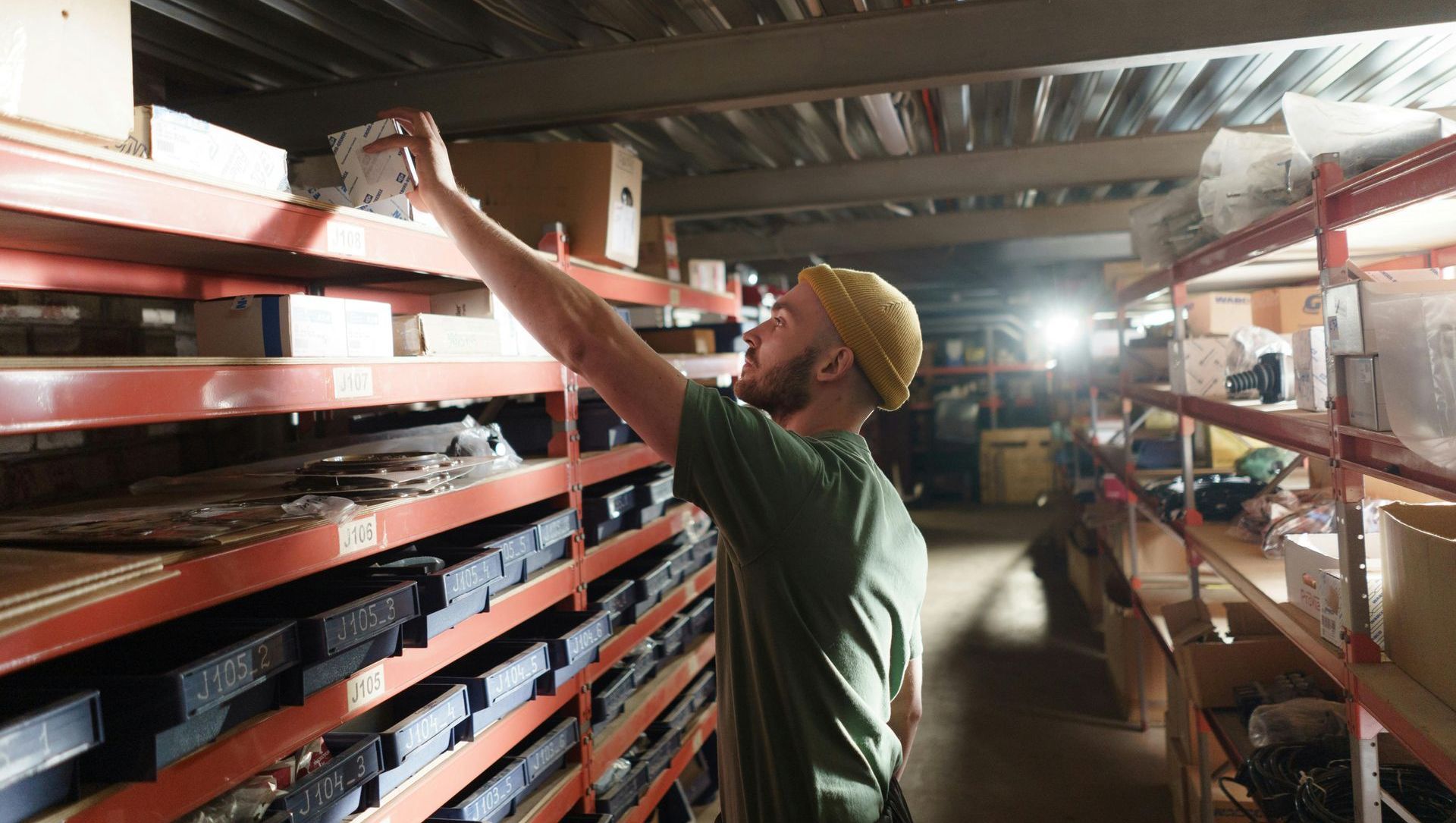 A man is reaching for something in a warehouse.