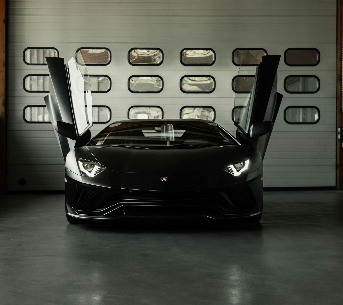 A black sports car is parked in a garage with its doors open