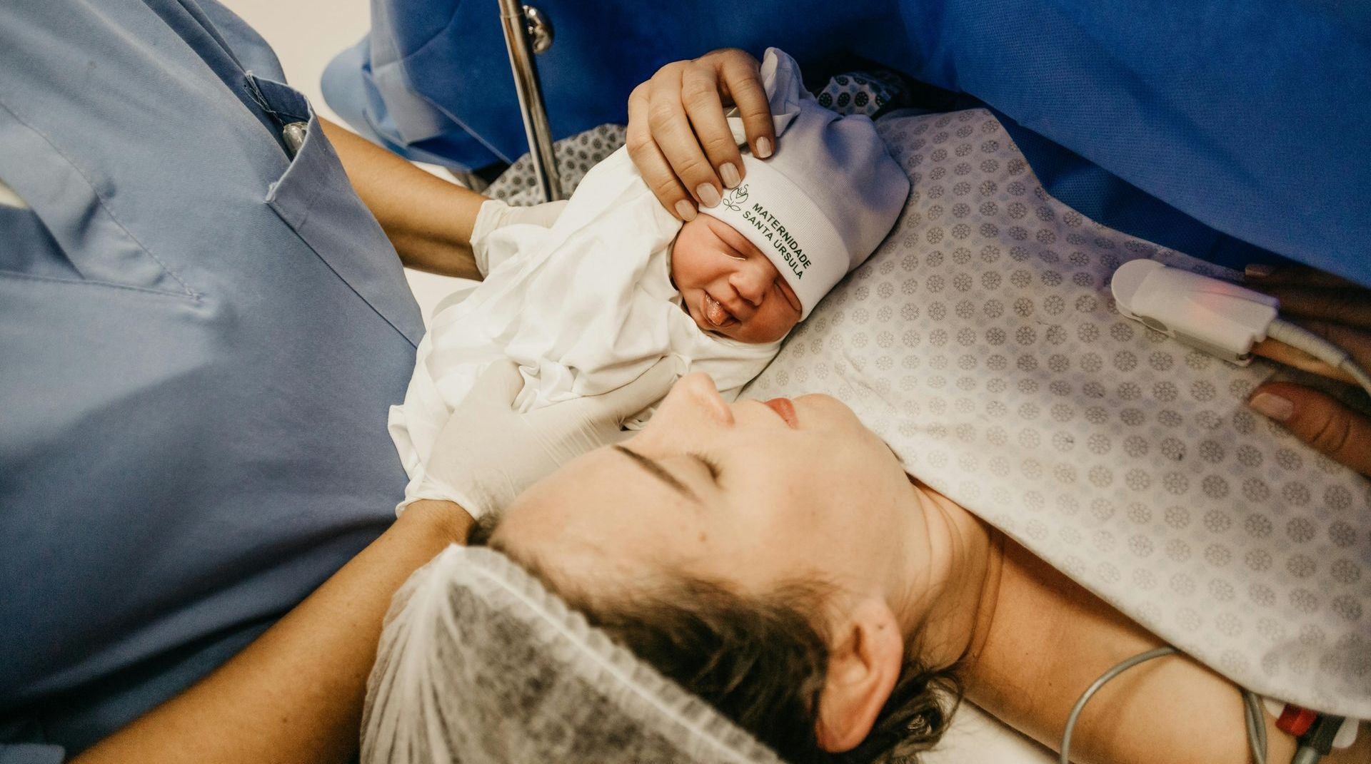 A woman is laying in an operating room with a newborn baby.