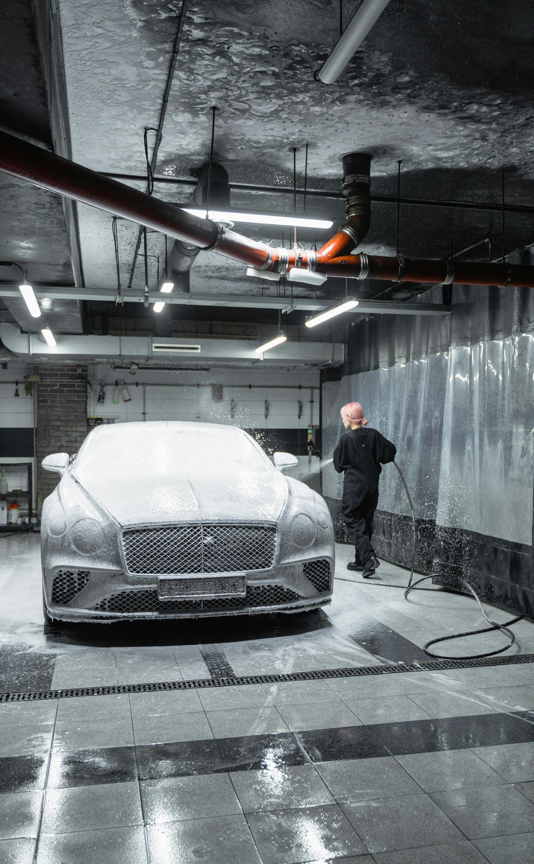 A man is washing a car in a garage.