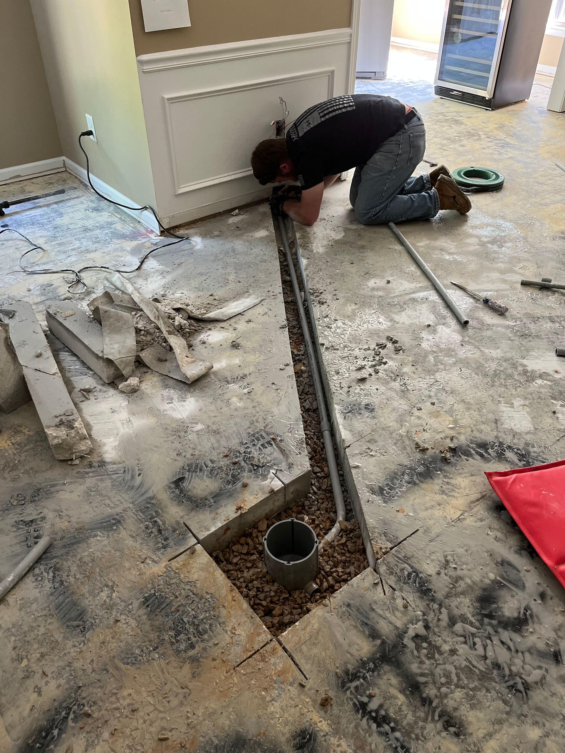 a man is kneeling on the floor working on a pipe .