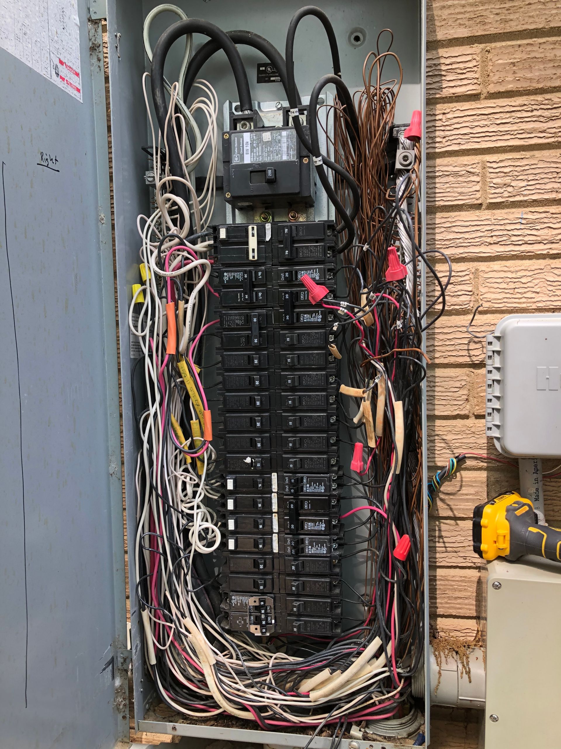 a very messy electrical box with a lot of wires coming out of it .