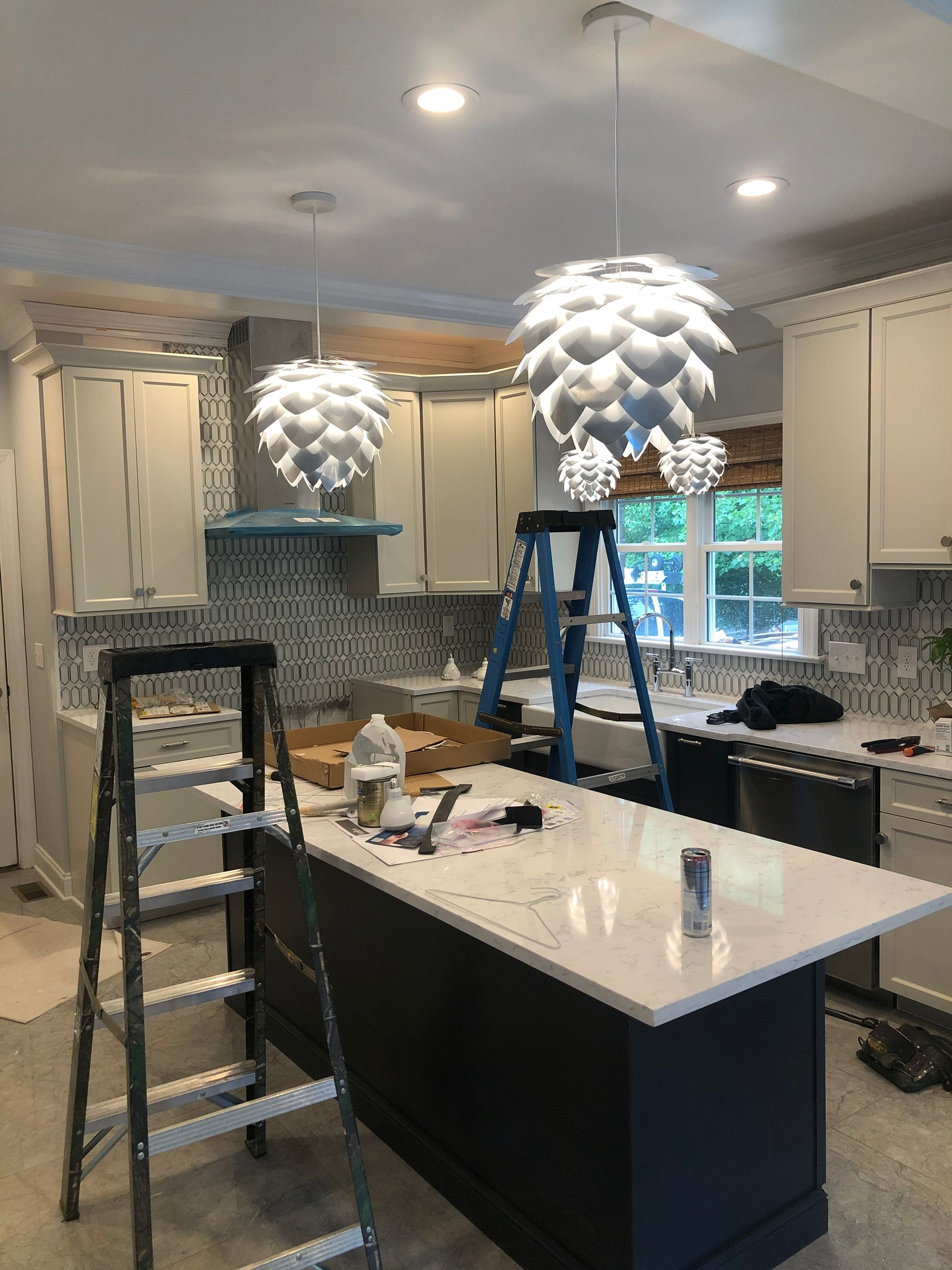 a kitchen under construction with a large island and a ladder .