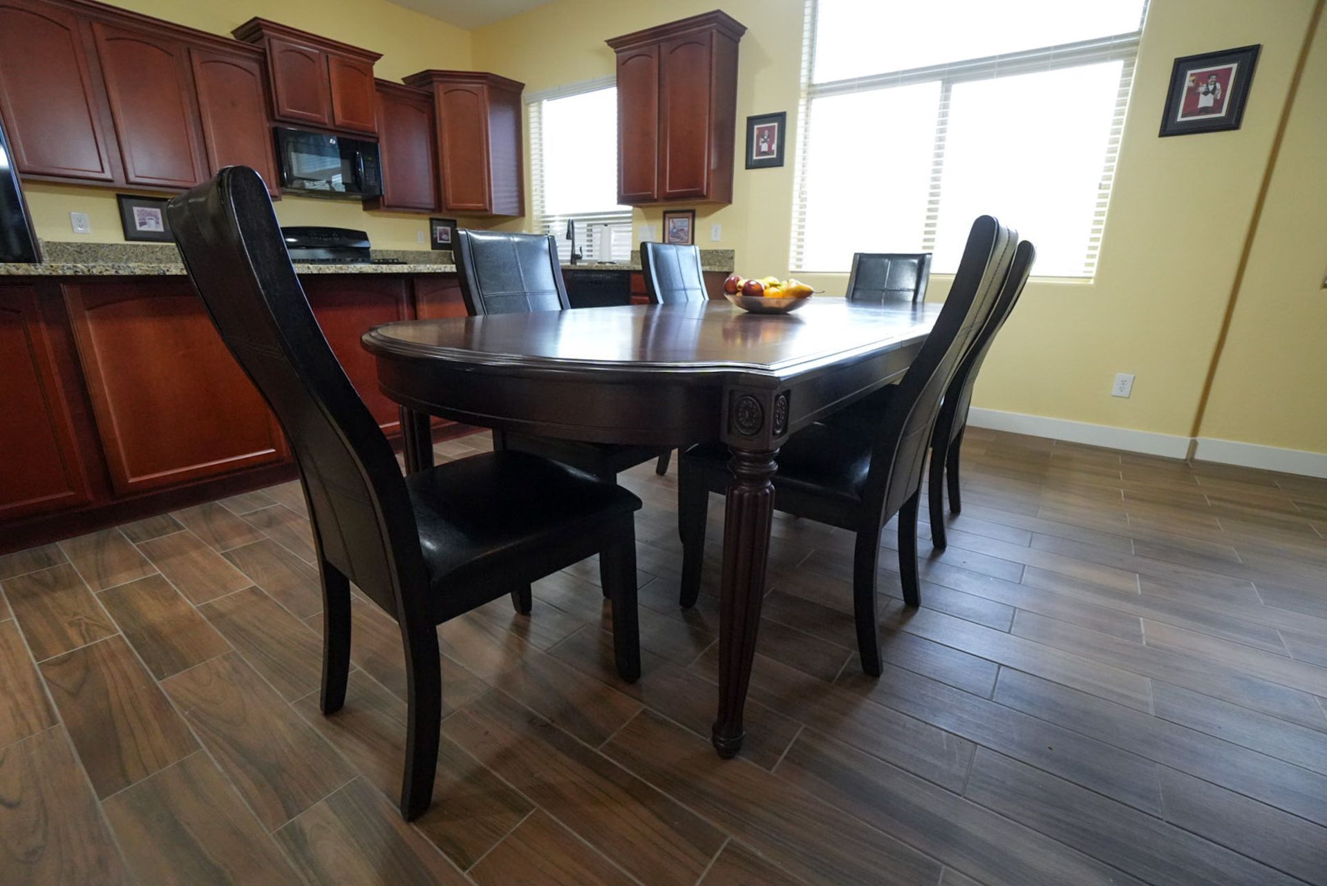 Dining room with dark wood table and chairs, brown cabinetry, and a window.
