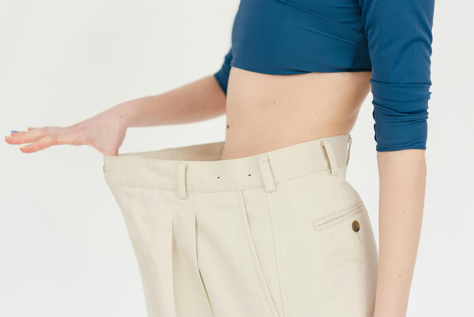 Una donna indossa un top corto blu e pantaloni color cachi.