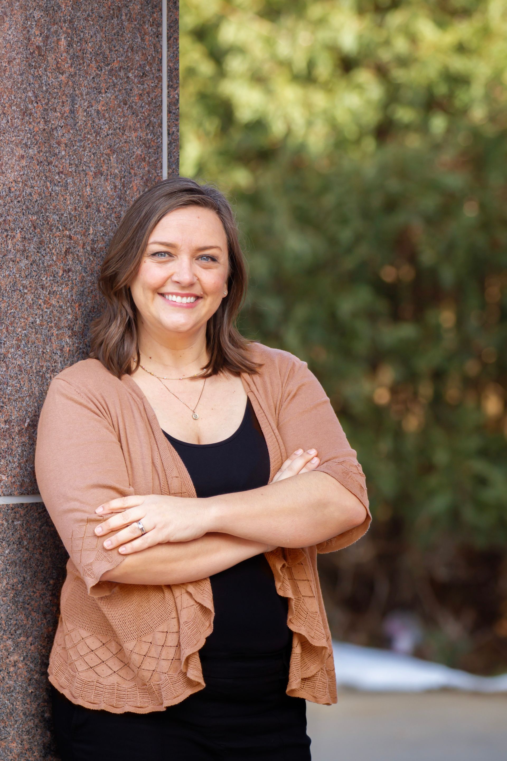 A professional woman in a peach sweater and black top is smiling for the camera.