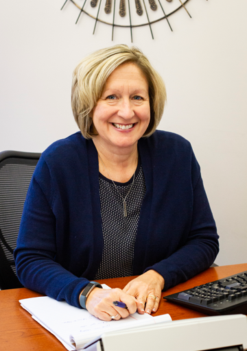 A woman is sitting at a desk with a pen in her hand.