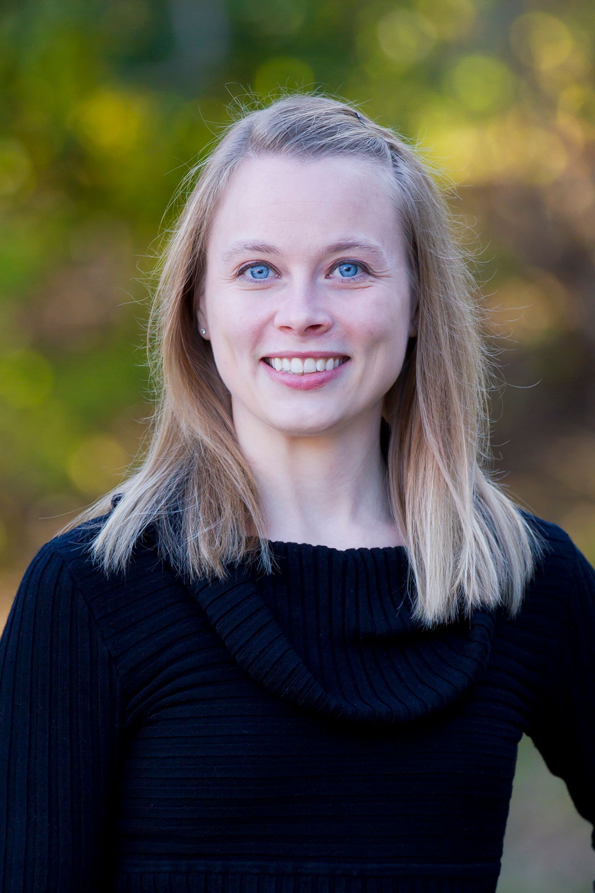 A woman in a black sweater is smiling for the camera.