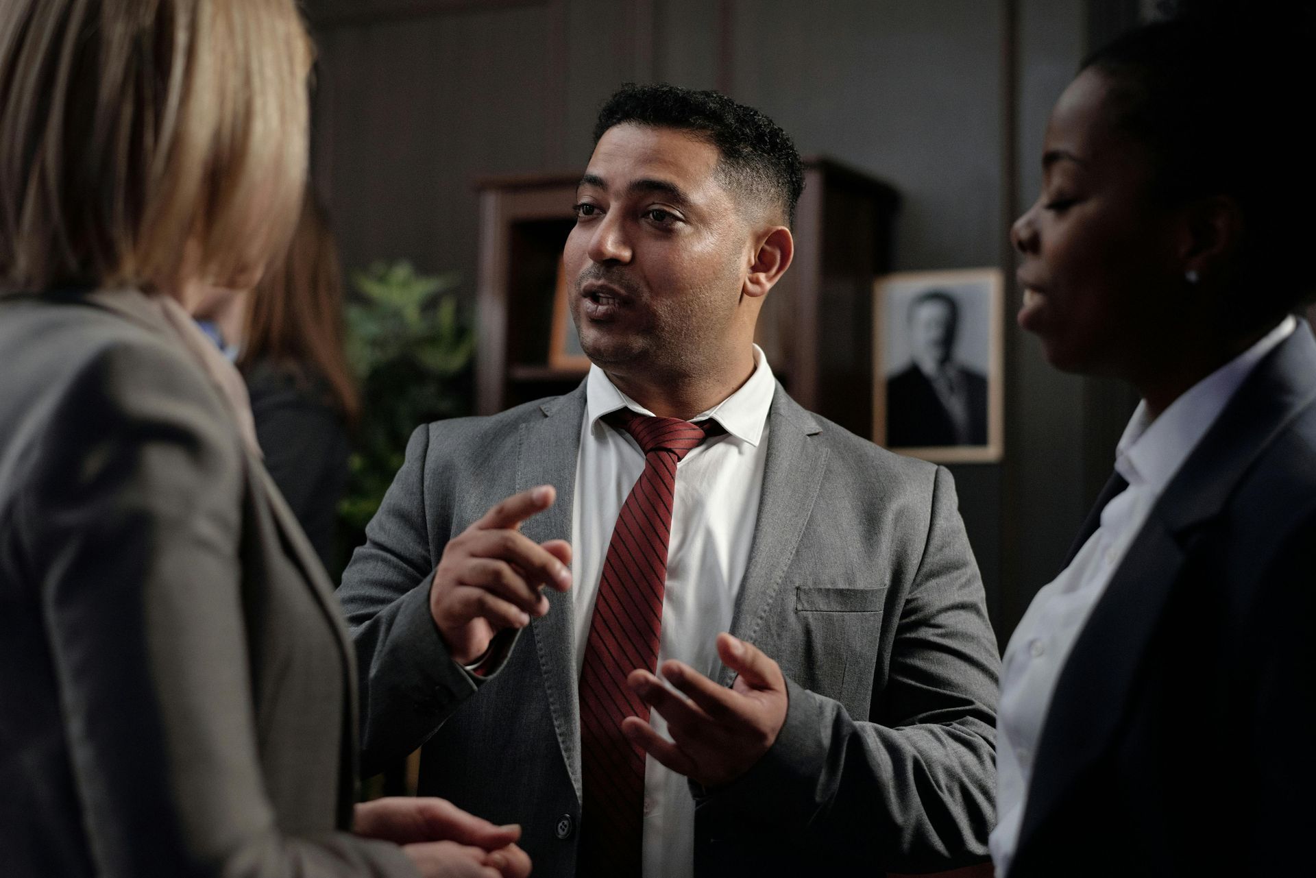 A man in a suit and tie is talking to two women.