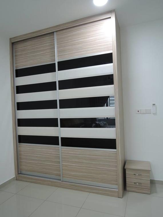 Sliding door closet with alternating black and white panels next to a small nightstand, set against a white wall.