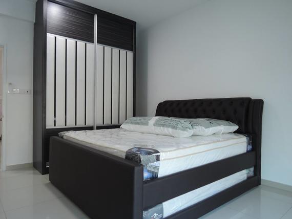 Bedroom with a dark bed frame, mattress, pillows, and a large wardrobe. White walls.
