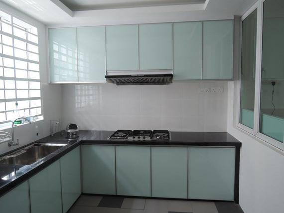 Light blue kitchen cabinets with black countertops, sink, and stove.