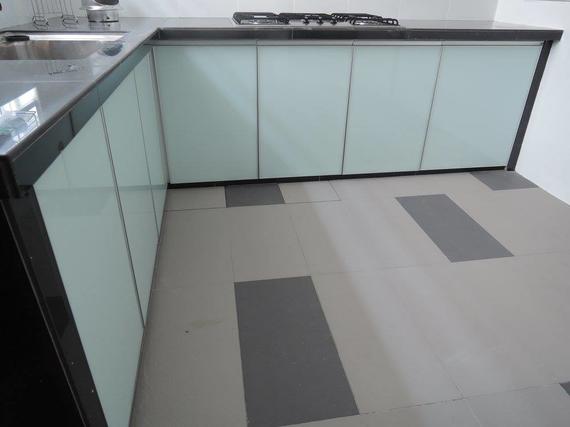Kitchen with light-colored cabinets and a dark countertop, featuring a gas stove. The floor has gray and darker gray tiles.