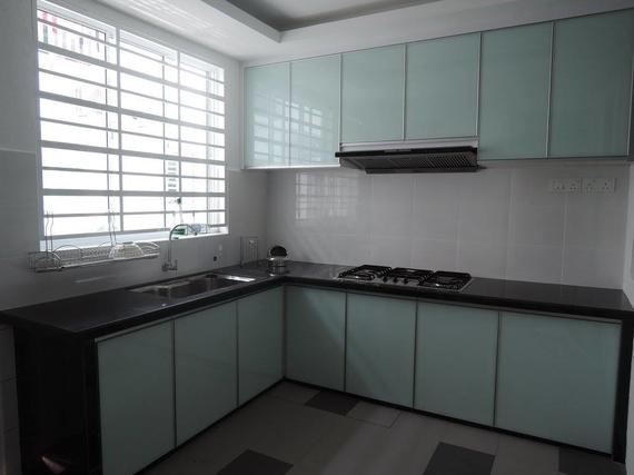 Modern kitchen with light blue cabinets, dark countertops, and a window.